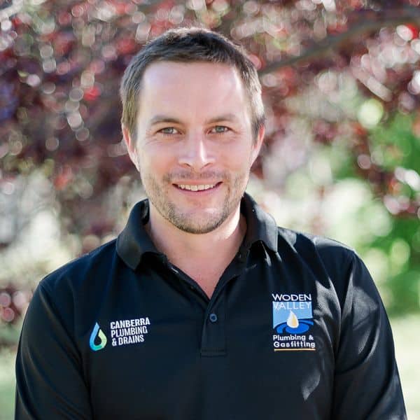 Andrew in Canberra Plumbing & Drains uniform smiling outdoors.
