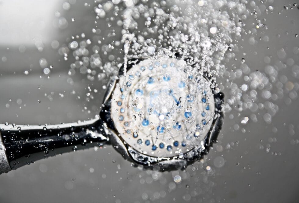 Shower head with water splashing, indicating hot water issues.