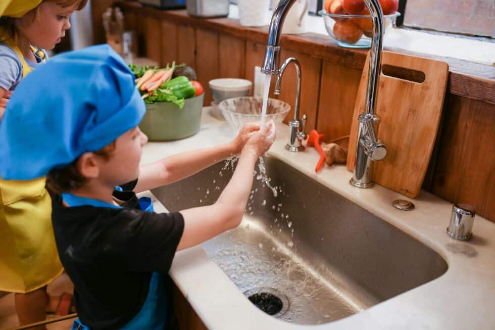 Water main repair in Canberra kitchen sink with children washing hands, emphasizing plumbing mainten.